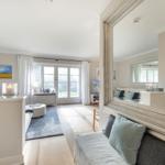 Living room with large windows, mirror, and sofa.