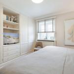 Bedroom with white wardrobe, TV, and bed. A large picture hangs on the wall.