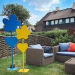 Garden with wicker furniture and colorful flower figures in front of a thatched house.
