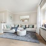Living room with white sofa, round ottoman, and window sill.