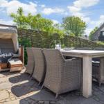 Terrace with garden furniture, sun shelter, and stone paving.