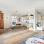 Living and dining area with wooden floor, dining table, and kitchen area.