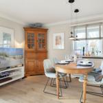 Dining room with round table, chairs, and TV. Wooden furniture and window with blinds.