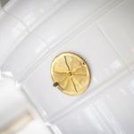 Goldener Ventilator auf weißer Fliesenwand