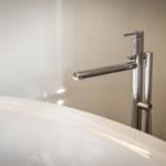 Moderne Dusche mit hochwertigem Wasserhahn und glänzendem Waschbeckenrand.