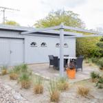 Graue Hütte mit Sitzgelegenheit unter Pavillon im Garten