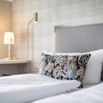 Schlafzimmer mit Bett, Kissen und Stehlampe.