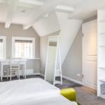 Schlafzimmer mit Dachschrägen, Schreibtisch und Kleiderschrank.