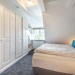 Schlafzimmer mit Doppelbett, Kleiderschrank und Fenster.