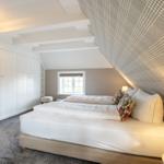 Schlafzimmer mit Dachschrägen, weißem Bett und Kleiderschrank