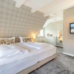 Schlafzimmer mit Doppelbett, TV und schräger Wandverkleidung.