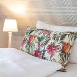 Bettkopfteil mit Muster, Kissen mit Blumenmotiv und Nachttischlampe.