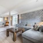 Wohnzimmer mit grauem Sofa, Holztisch und blau-weißem Tapetenwand.