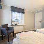 Ein Schlafzimmer mit Bett, Stuhl und TV vor dem Fenster.