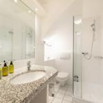 Badezimmer mit Dusche, Toilette und Waschbecken mit Spiegel