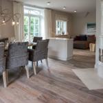 Dining room with table, chairs, and windows. Living area with sofa and fireplace.