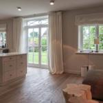 Living and dining area with wooden floor, windows, and a kitchen island.