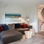 A living room with sofa, wall art, and staircase.