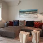A living room with gray sofa, red and blue cushions, wooden tables, and wall art.