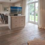 Living and dining area with TV stand, wooden floor, and glass doors to terrace.