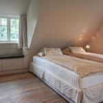 Bedroom with double bed, window, and wooden floor.