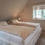 Bedroom with double bed, window, and wooden floor.