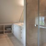 Bathroom with shower and sink. White cabinets and tiles.