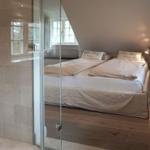 Bedroom with double bed, glass wall, and wooden floor.