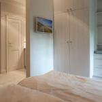Bedroom with bed, wardrobe, and shelving. Wall art shows beach.