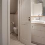 Bathroom with sink, mirror and toilet in continuation
