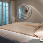 Bedroom with double bed, window, and wall mirror.