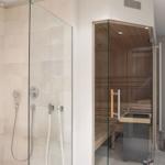 Shower with glass enclosure and sauna with wooden benches