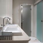 Bathroom with two sinks, mirror, and shower with glass door.