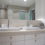 Double sink with mirrors and cabinets in modern bathroom setup.