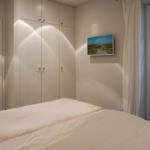 Bedroom with bed, wardrobe, and window. Passage to sauna visible.