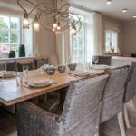 Dining room with table, chairs, and windows. Pendant lamp and bench are visible.