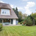 Haus mit Strohdach, großem Garten und Glasfront zur Terrasse.