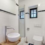 Badezimmer mit Dusche, Toilette und Waschbecken auf Holzuntersetzer.