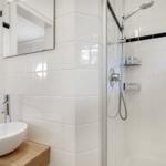 Badezimmer mit Dusche, Waschbecken und Spiegel