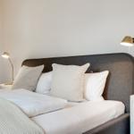 Schlafzimmer mit Bett, Kissen und Nachttischen mit Lampen.