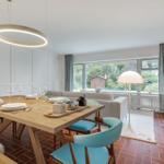 Esszimmer mit Holztisch, blauen Stühlen und großem Fenster zur Gartenansicht.