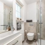 Bathroom with shower, sink, and toilet. Window and Buddha picture visible.
