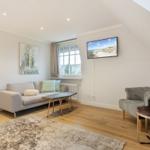 Living room with sofa, armchair, TV, and wooden floor.