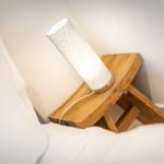 A lamp on a wooden table next to a bed