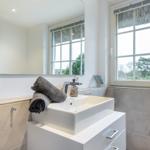 Bathroom with sink, mirror, and window with thatched roof view.