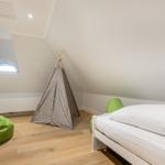 Bedroom with sloped ceiling, bed, teepee, and green bean bags.