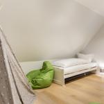 Bedroom with sloped ceiling, bed, green bean bag, and teepee.