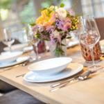 Table with white plates, glasses, and flower arrangement.