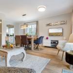 Living and dining area with wooden floor, TV, seating, and large windows.