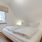 Schlafzimmer mit Doppelbett, zwei Nachttischen und Fenster mit Rollladen.
